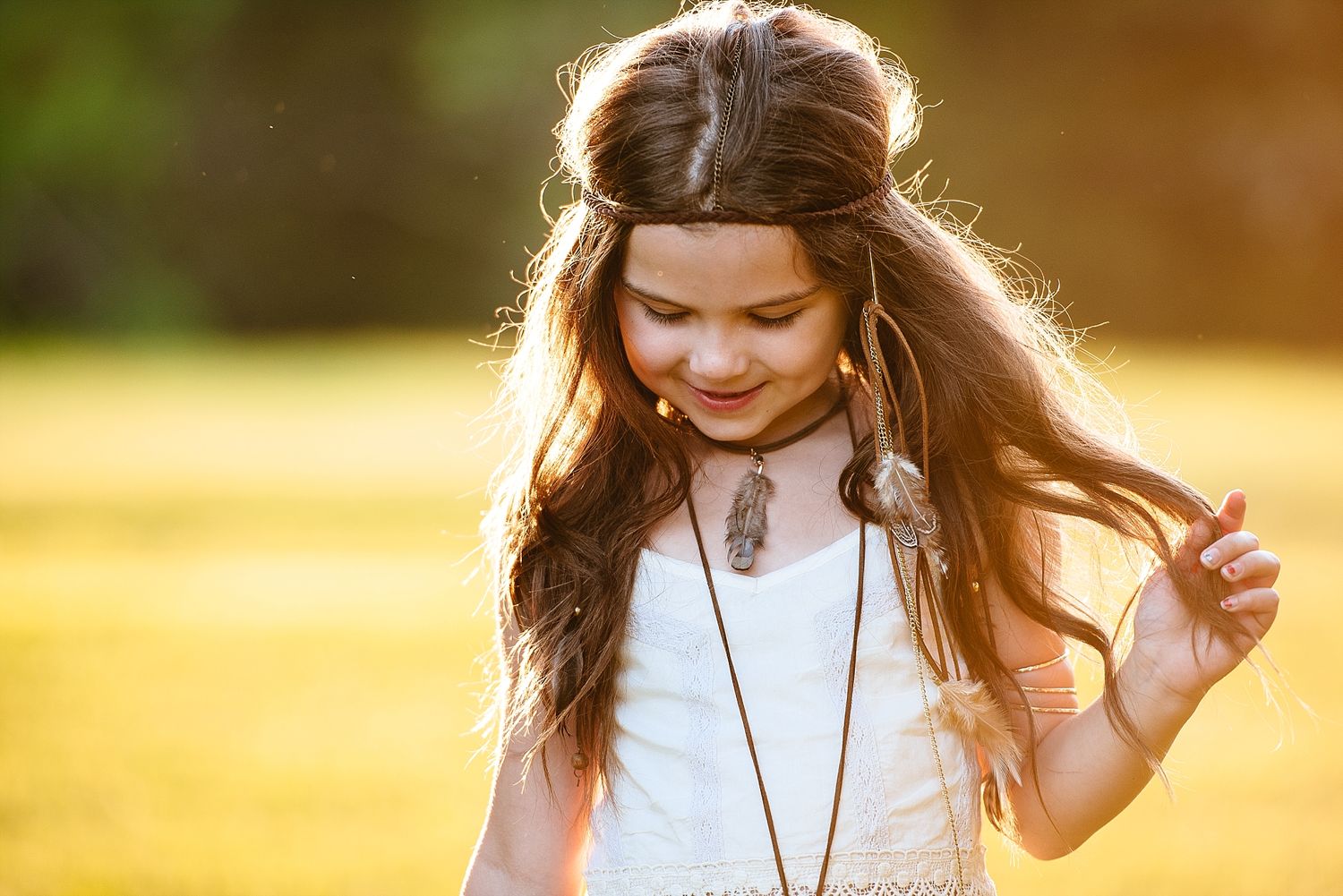Long brown hair flows in the sunlight as a white dress moves in the summer breeze.