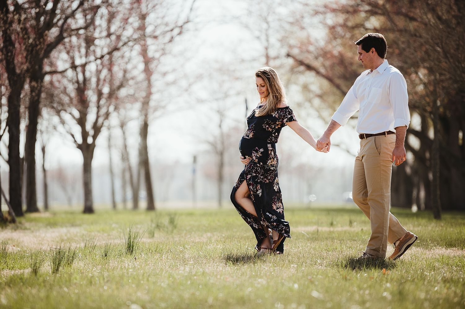 Couple in floral dress and casual attire holding hands in scenic autumn field.