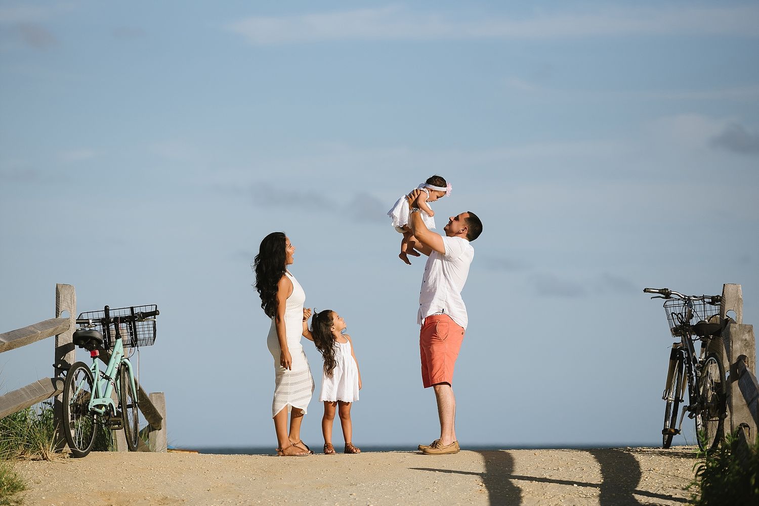 Family enjoying sunset moment on coastal path with bicycles nearby.