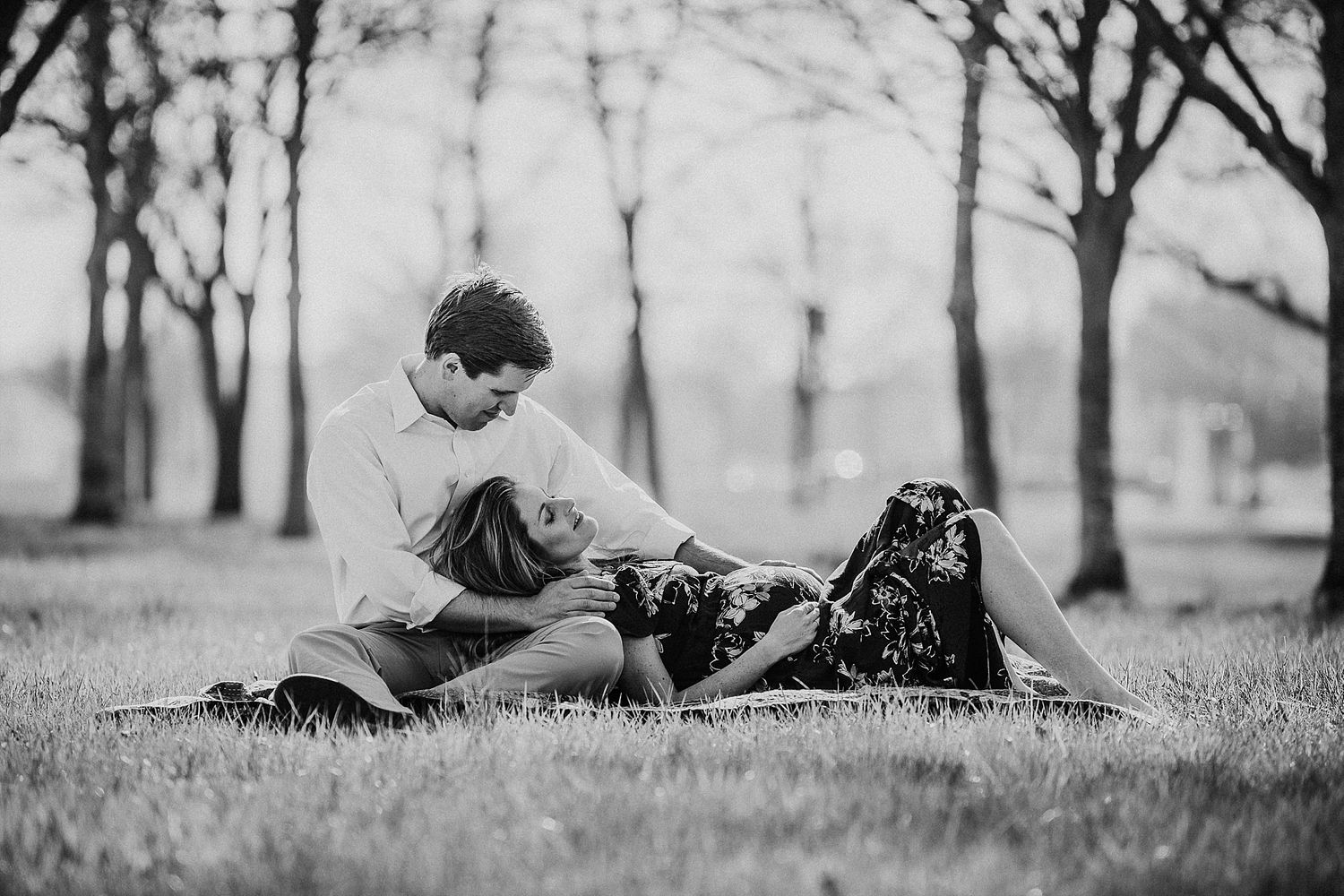 Child reading book on blanket in black and white park setting.