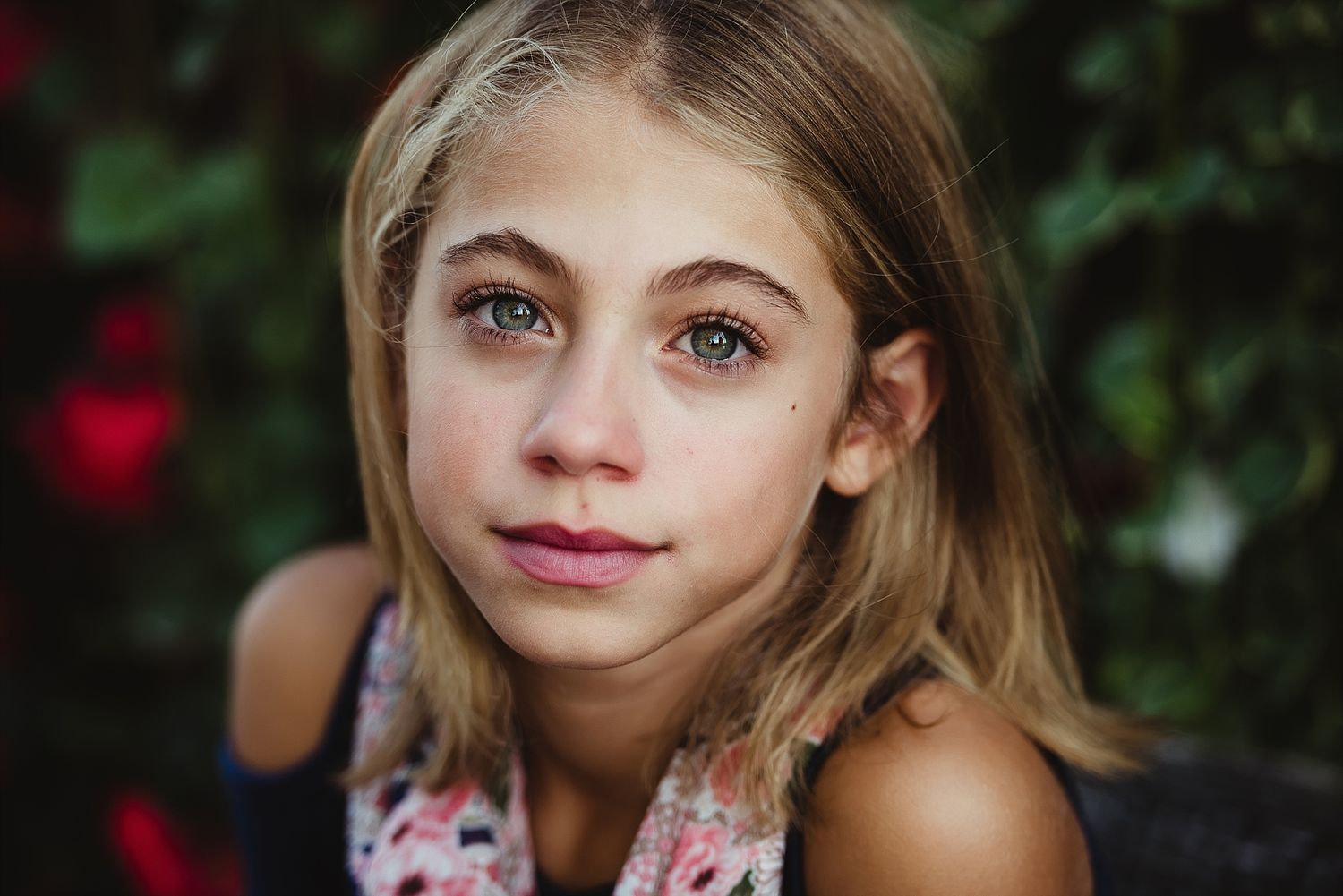 Close up portrait photo with soft natural lighting and blurred floral background.