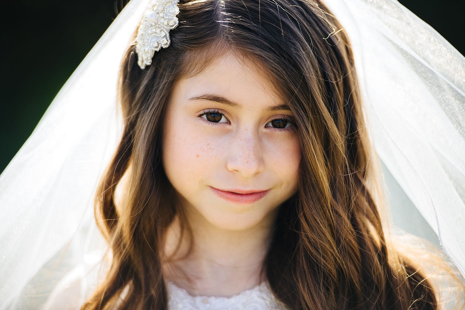 Portrait in soft lighting with white lace veil and hair accessory details.