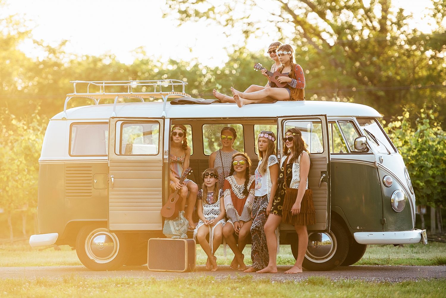 A group poses together around a vintage Volkswagen bus during golden hour.