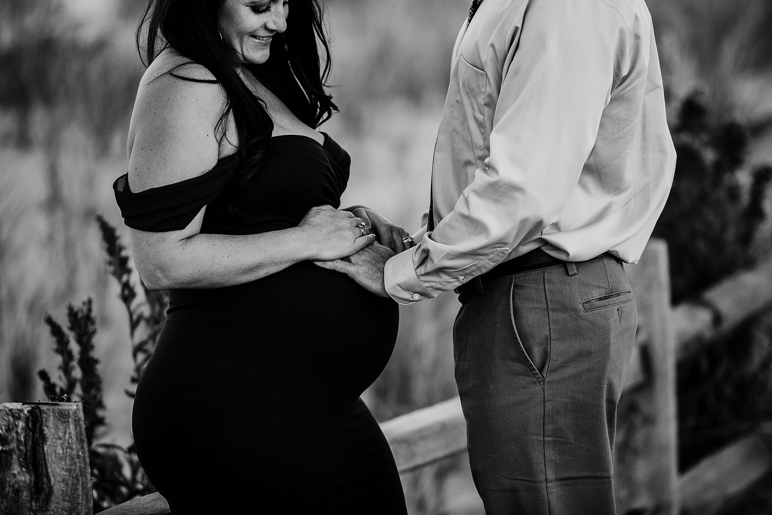 A black and white maternity photo of an expecting couple sharing an intimate moment.