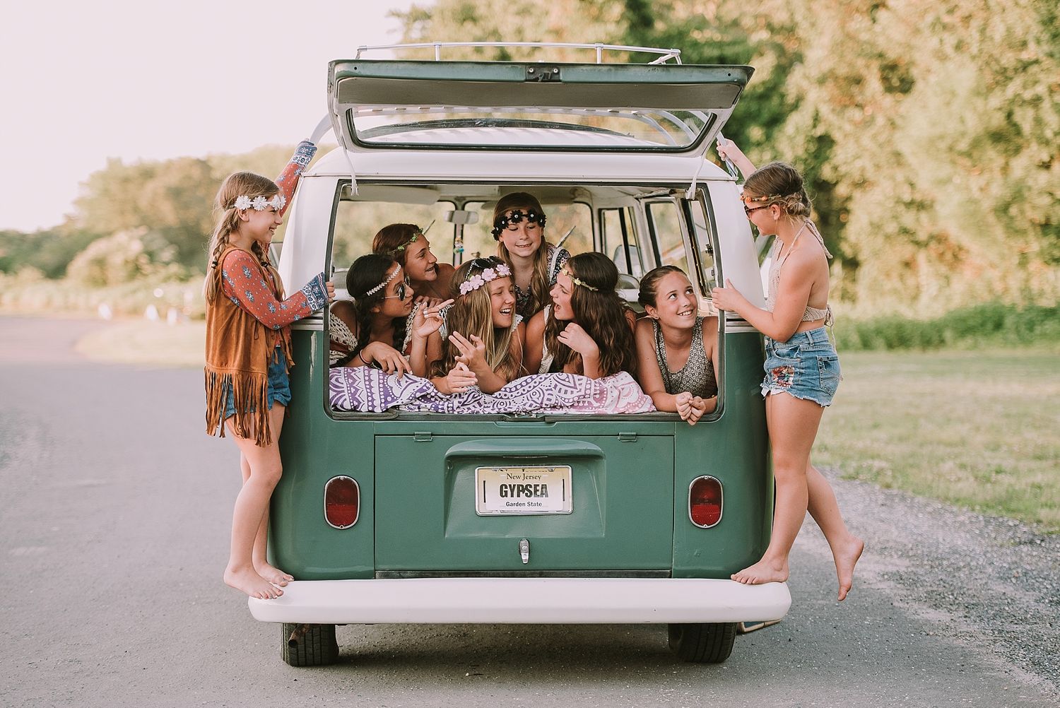 Friends gathered in the back of a mint green vintage Volkswagen van on a summer day.