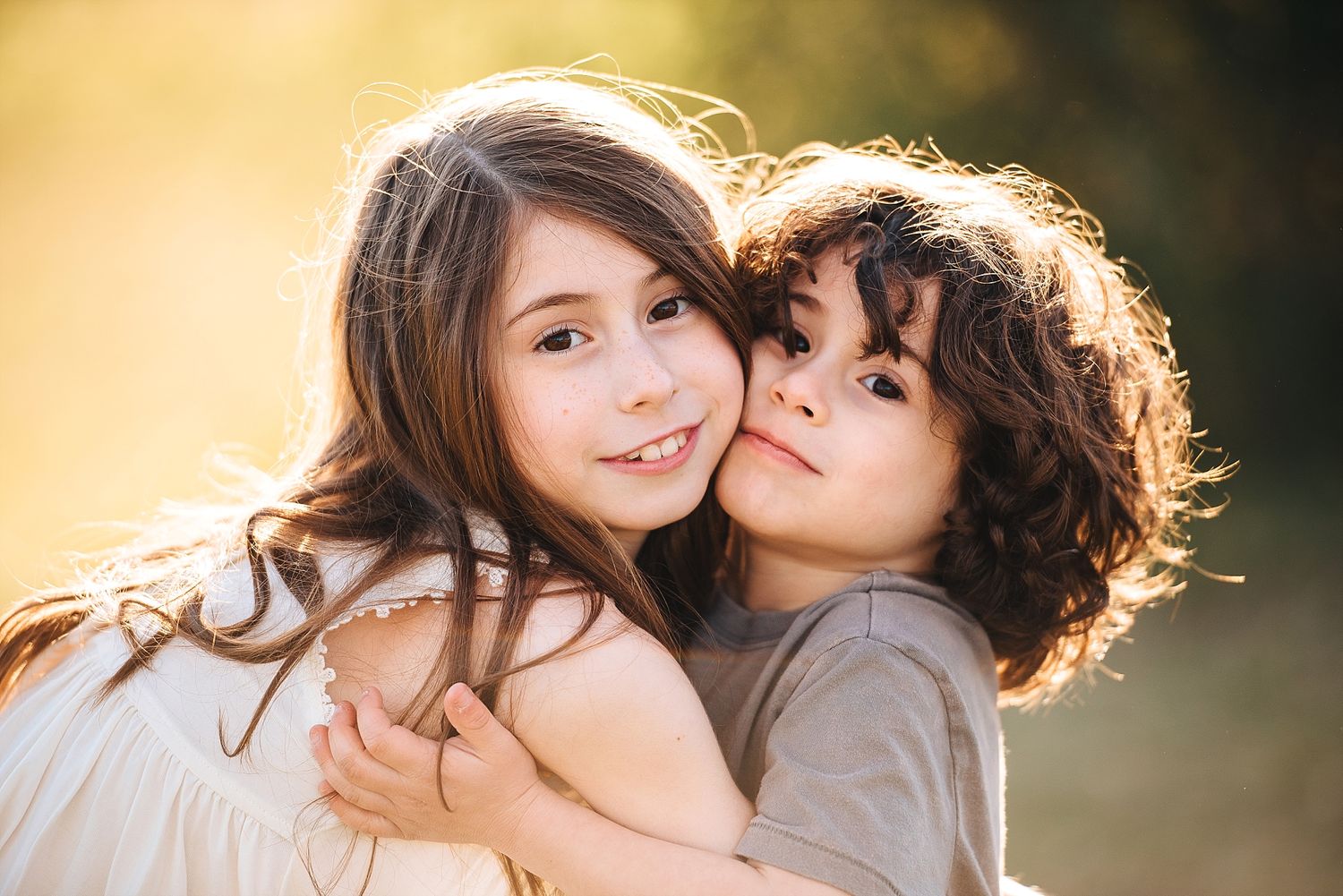 Two young people embracing in warm sunset lighting outdoors.