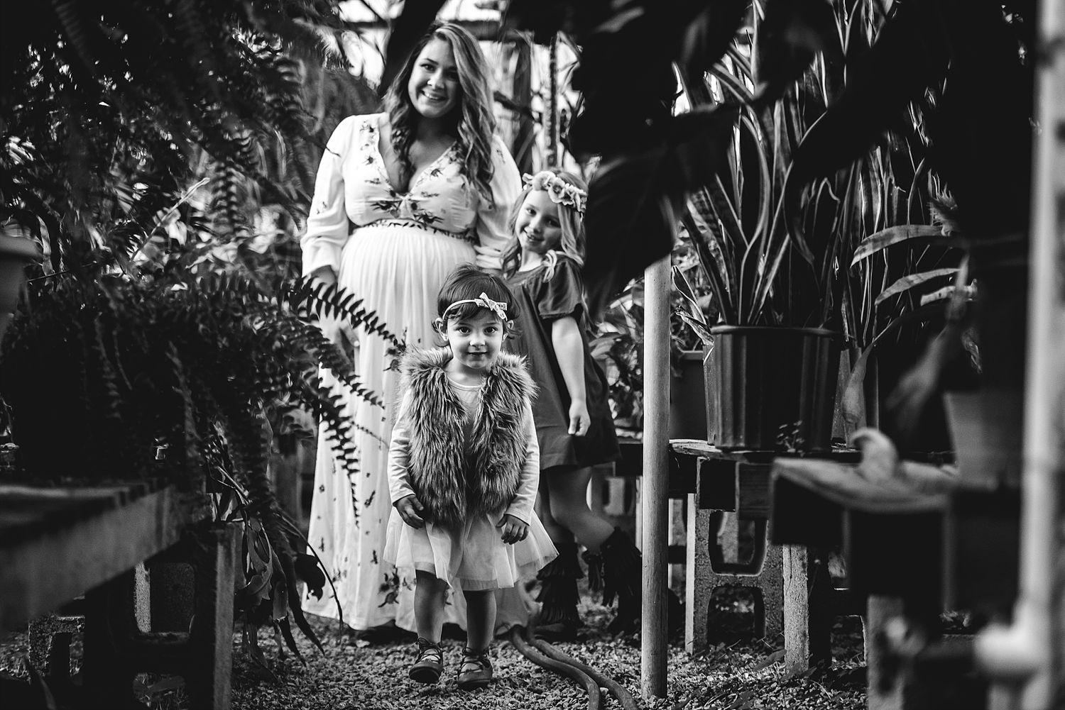 Black and white image of people walking through garden with plants.