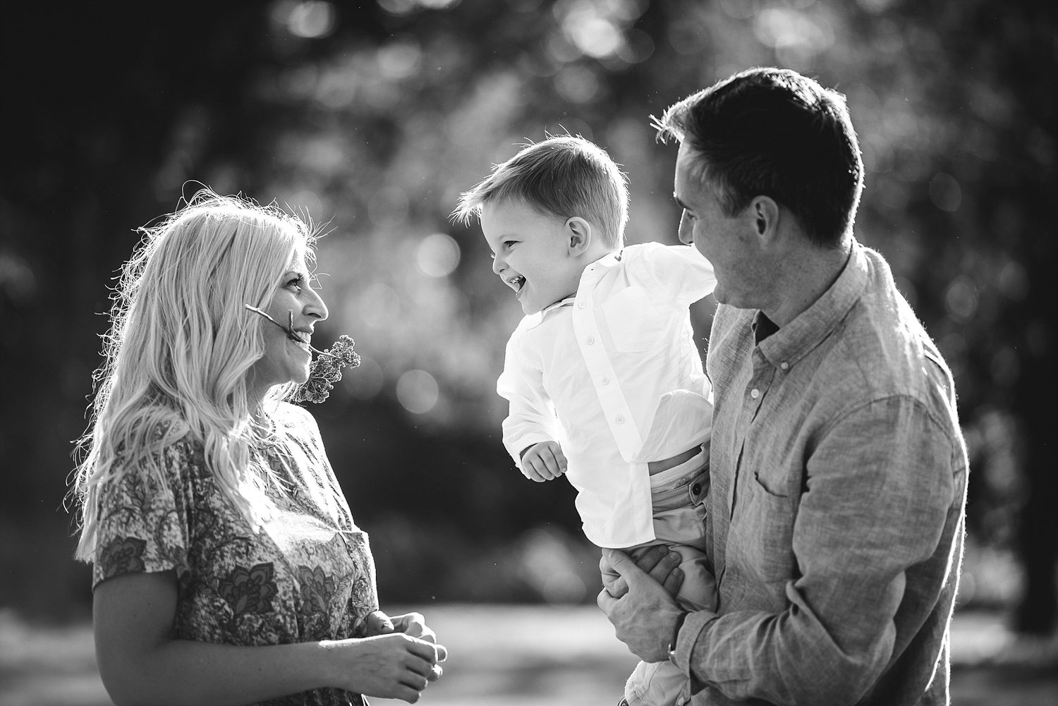 Black and white portrait of family sharing tender moment outdoors.