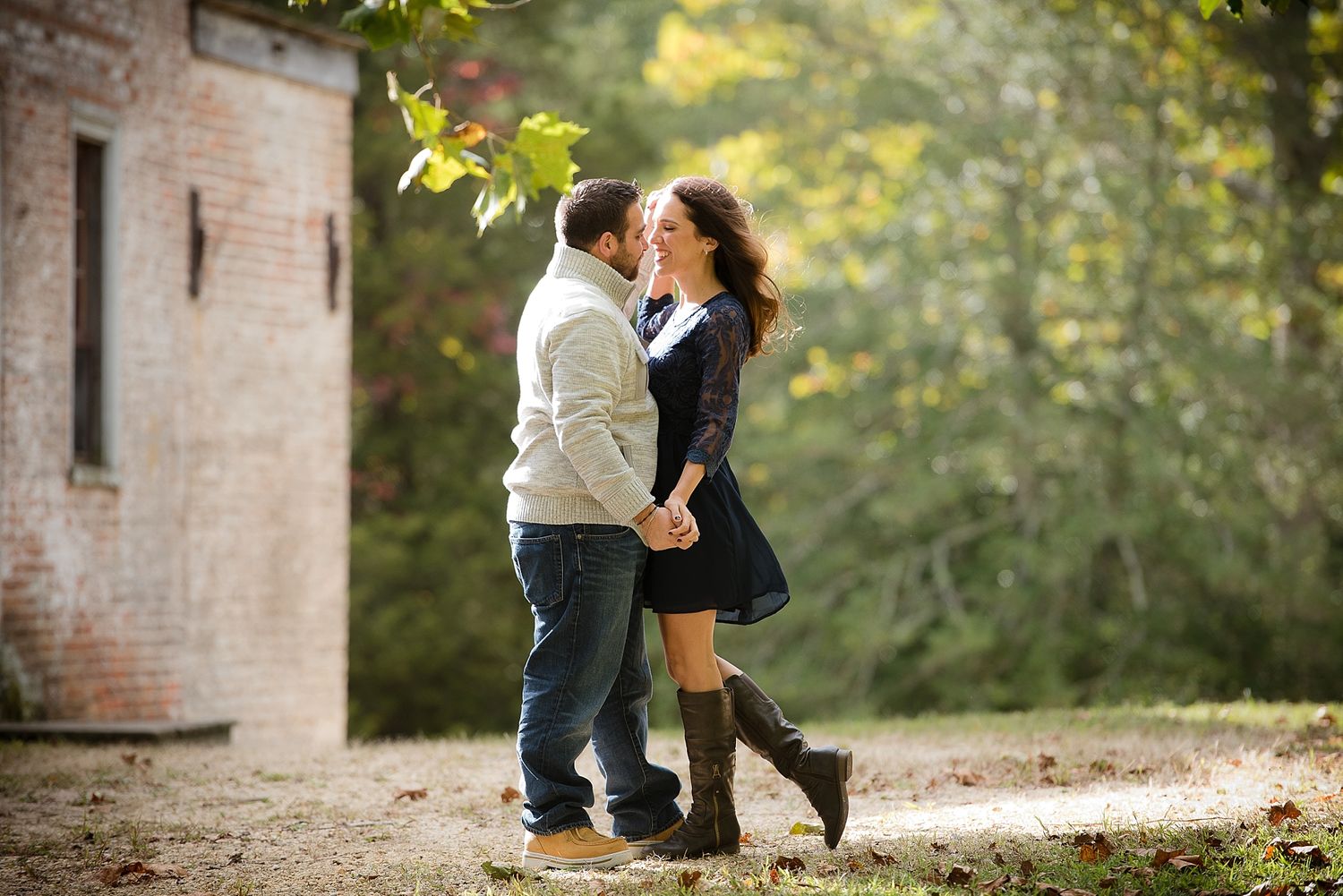 Couple embracing near brick building during romantic autumn photoshoot.