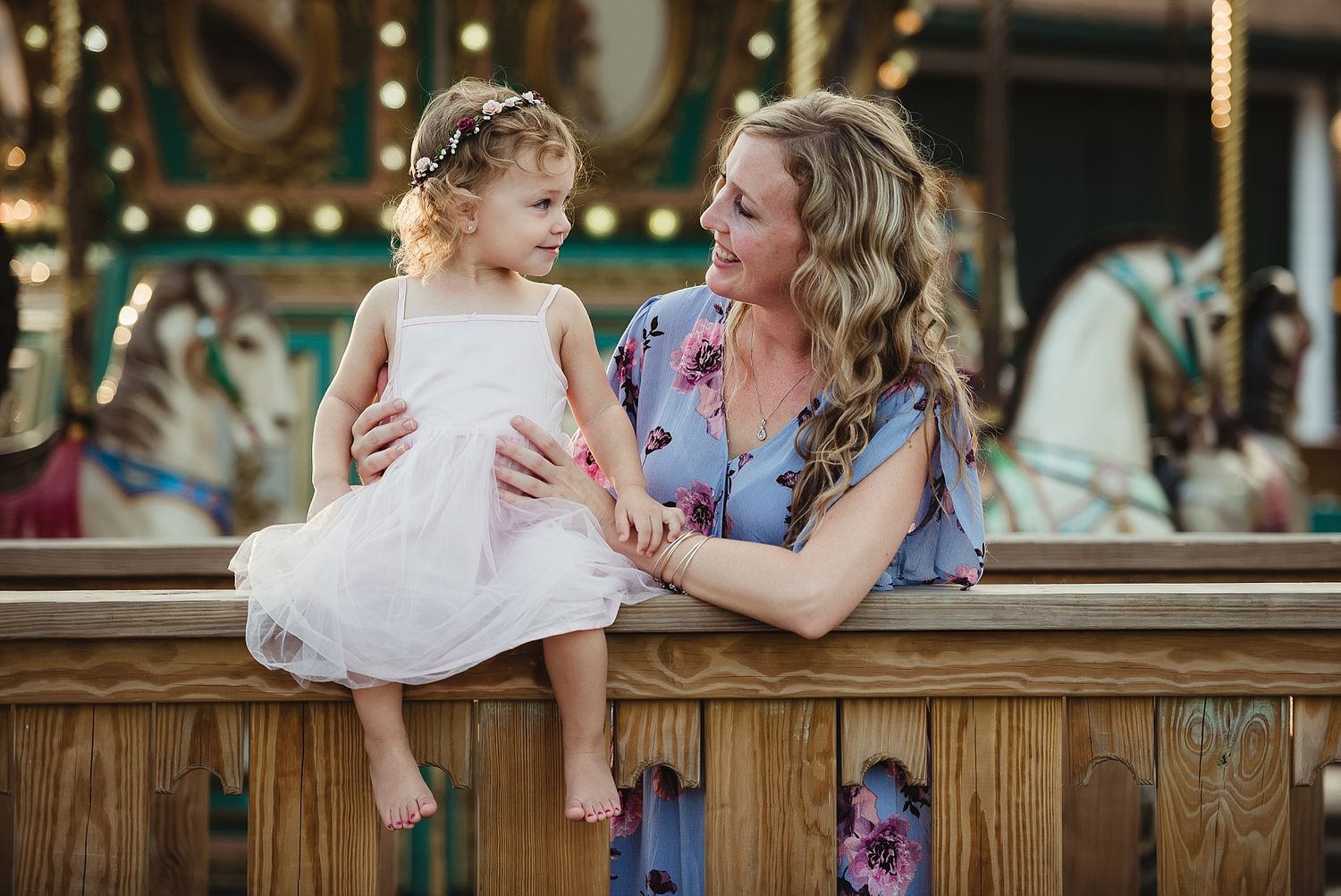 Mother and daughter share special moment at carnival near carousel.