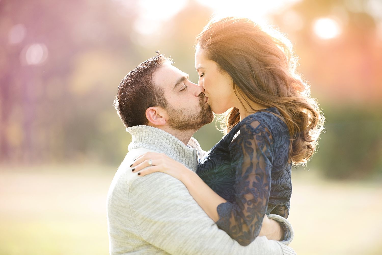 A romantic couple embracing in golden sunset light with soft bokeh effects.