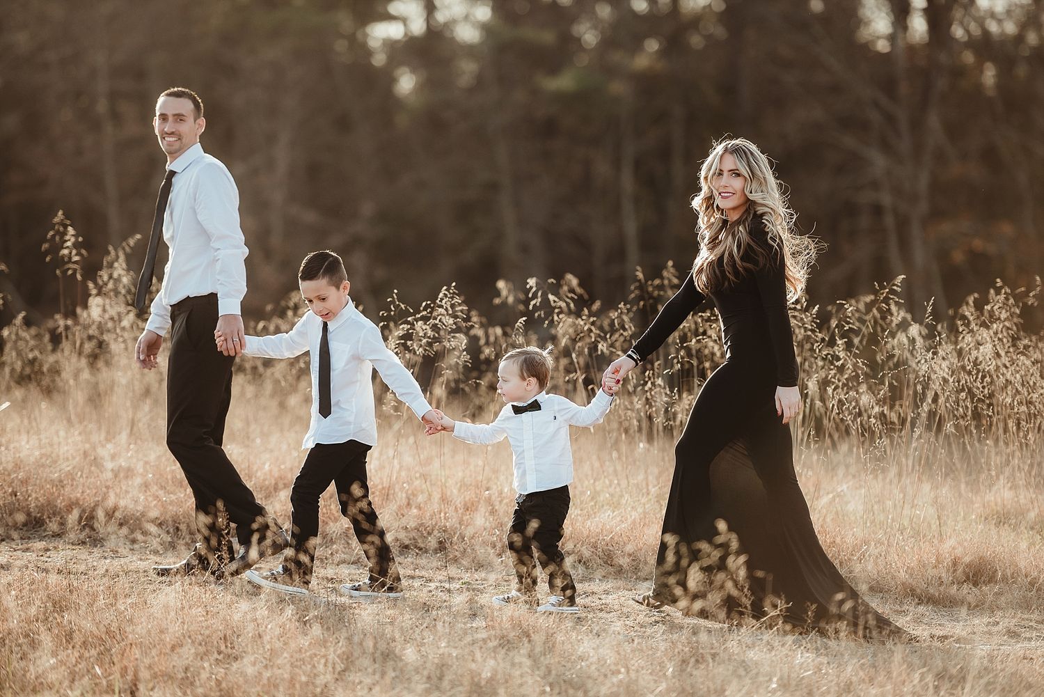 A family walking through tall grass in a field at sunset.