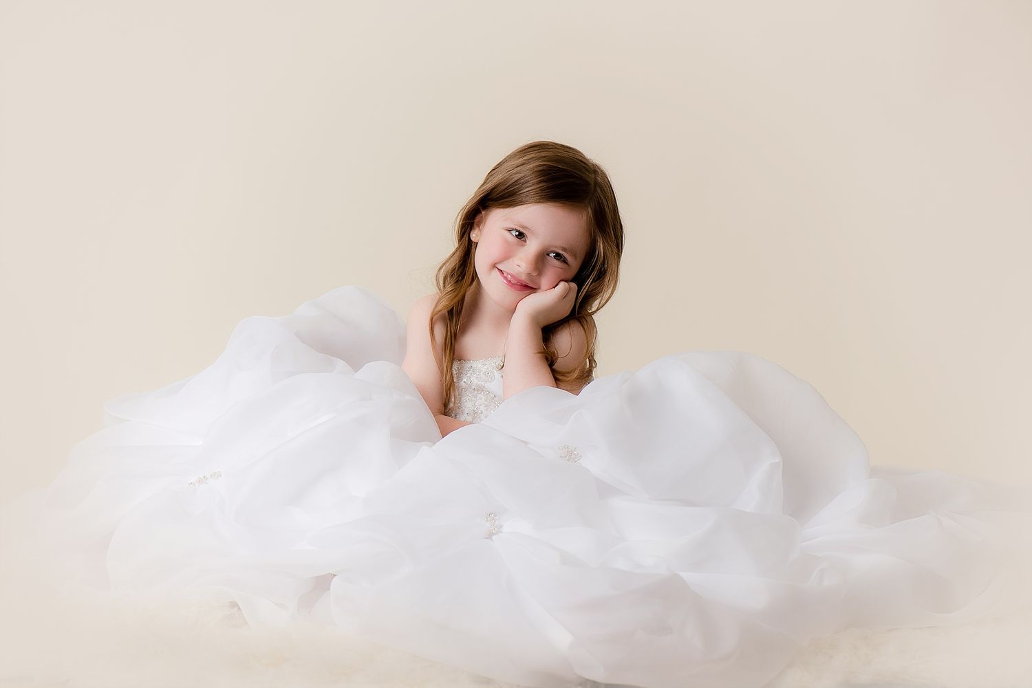 A dreamy portrait featuring layers of soft white tulle fabric against a neutral background.