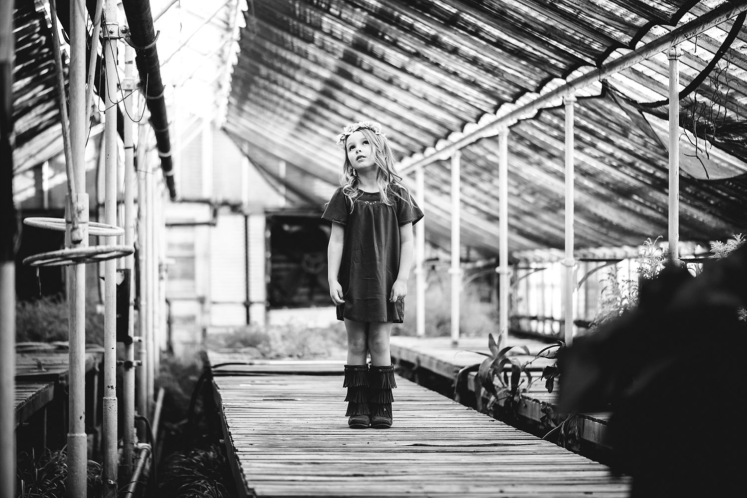 A dramatic black and white photo of someone standing on wooden planks in an industrial setting.