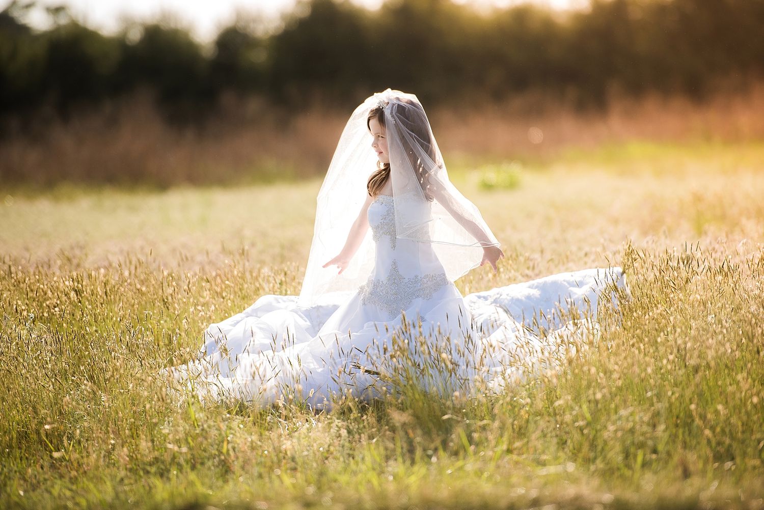 Bride in white dress twirling in sunny meadow during golden hour.