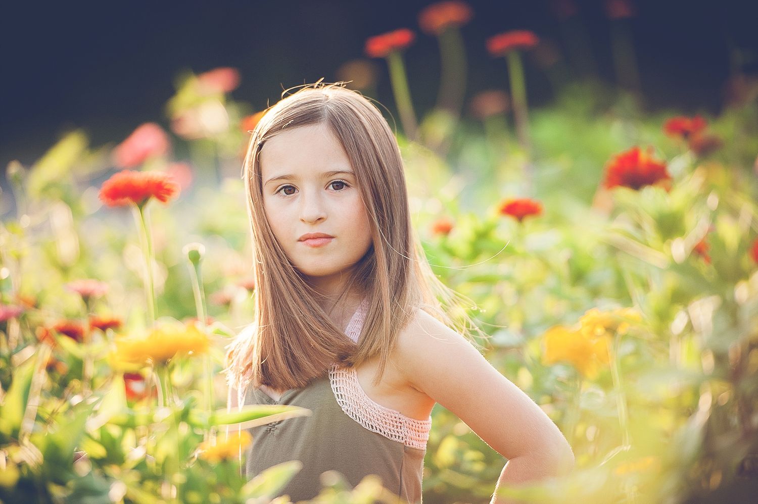 A dreamy portrait in a wildflower field with orange and red poppies in soft focus.