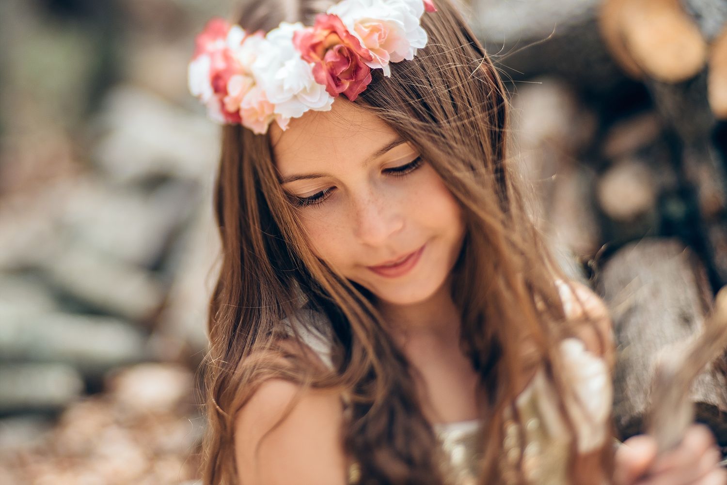 A person wearing a floral crown poses with flowers in soft focus.
