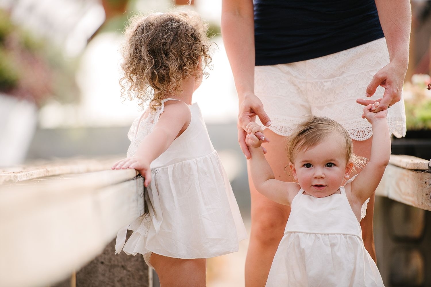 Two young children in white dresses standing together outdoors.