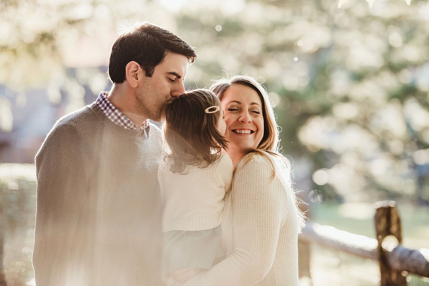 Family sharing tender moment together in warm sunlight.