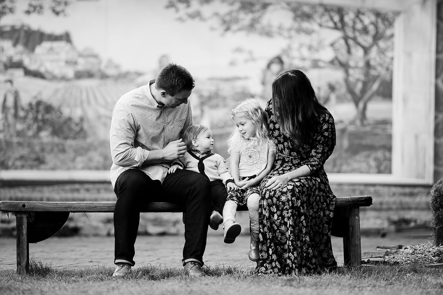 Family sharing intimate moment together on park bench in black and white.