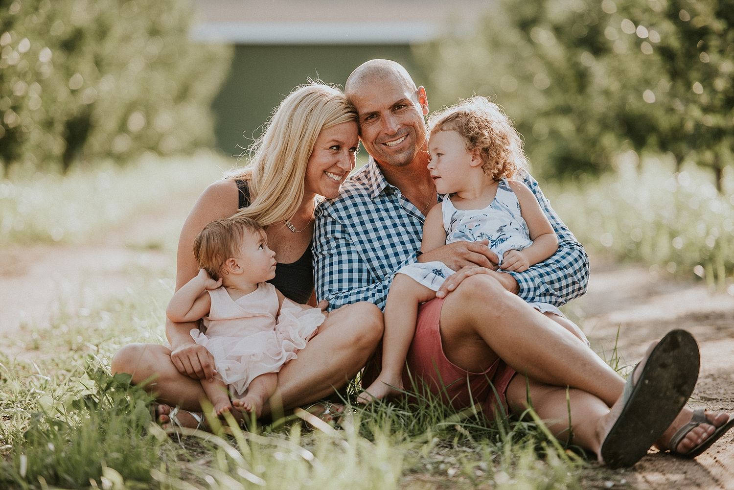 Family relaxing together on grassy field during golden hour.