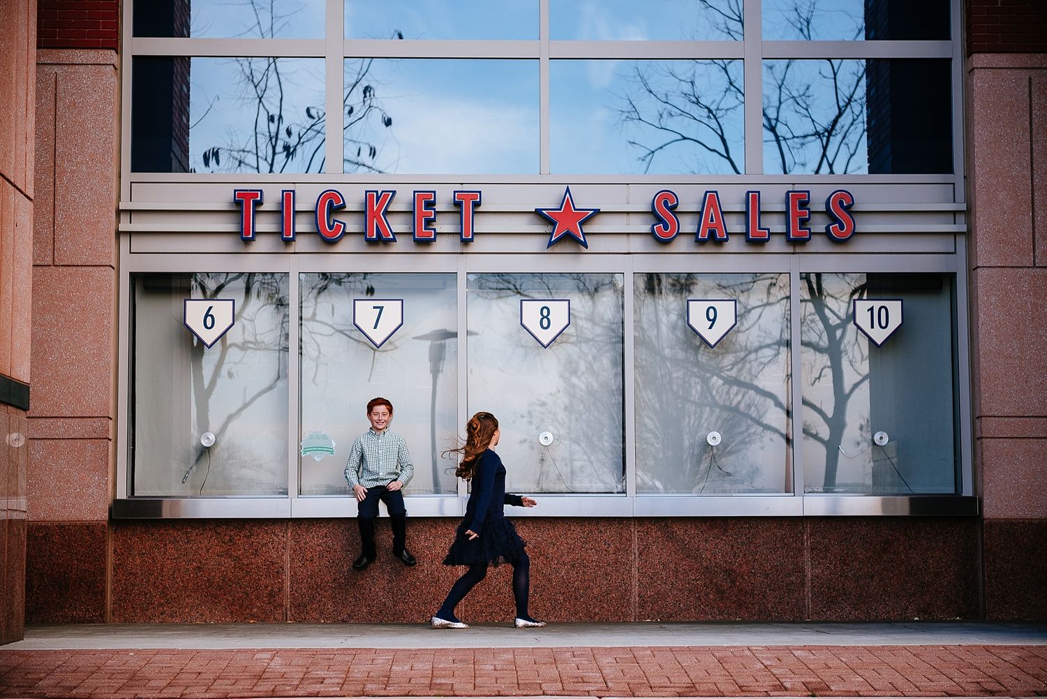 Children running past ticket sales storefront with red signage.