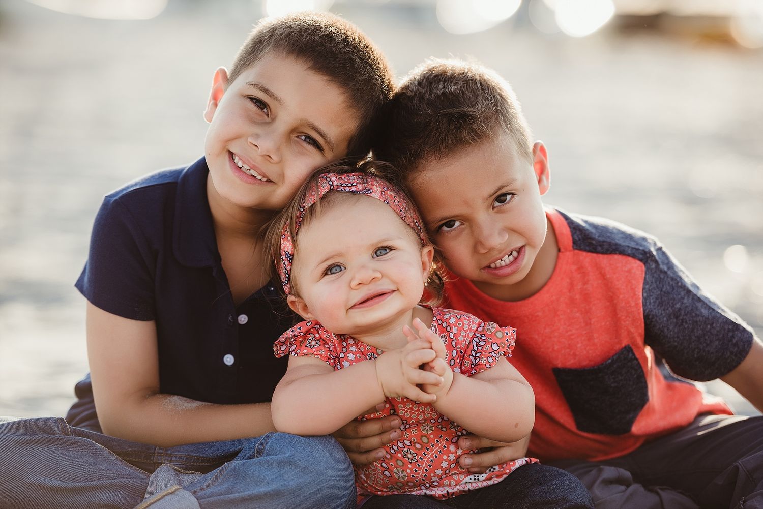 Three siblings posing together in warm outdoor lighting.