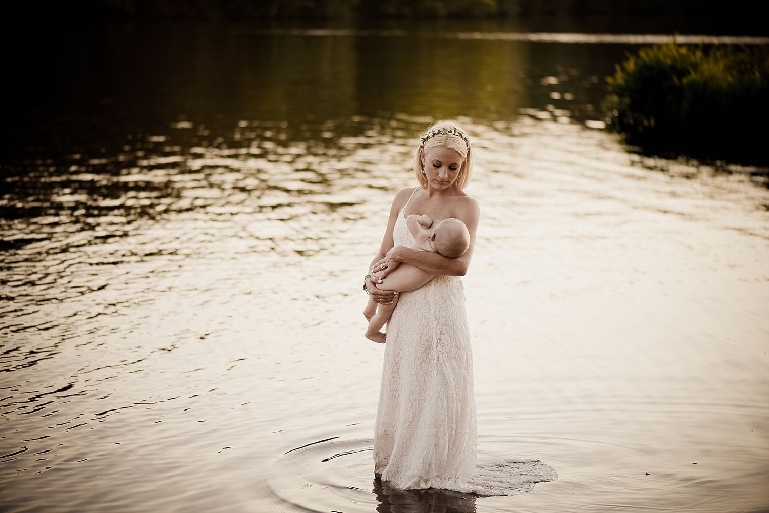 A person in a white dress stands in shallow water during a sunset photoshoot.