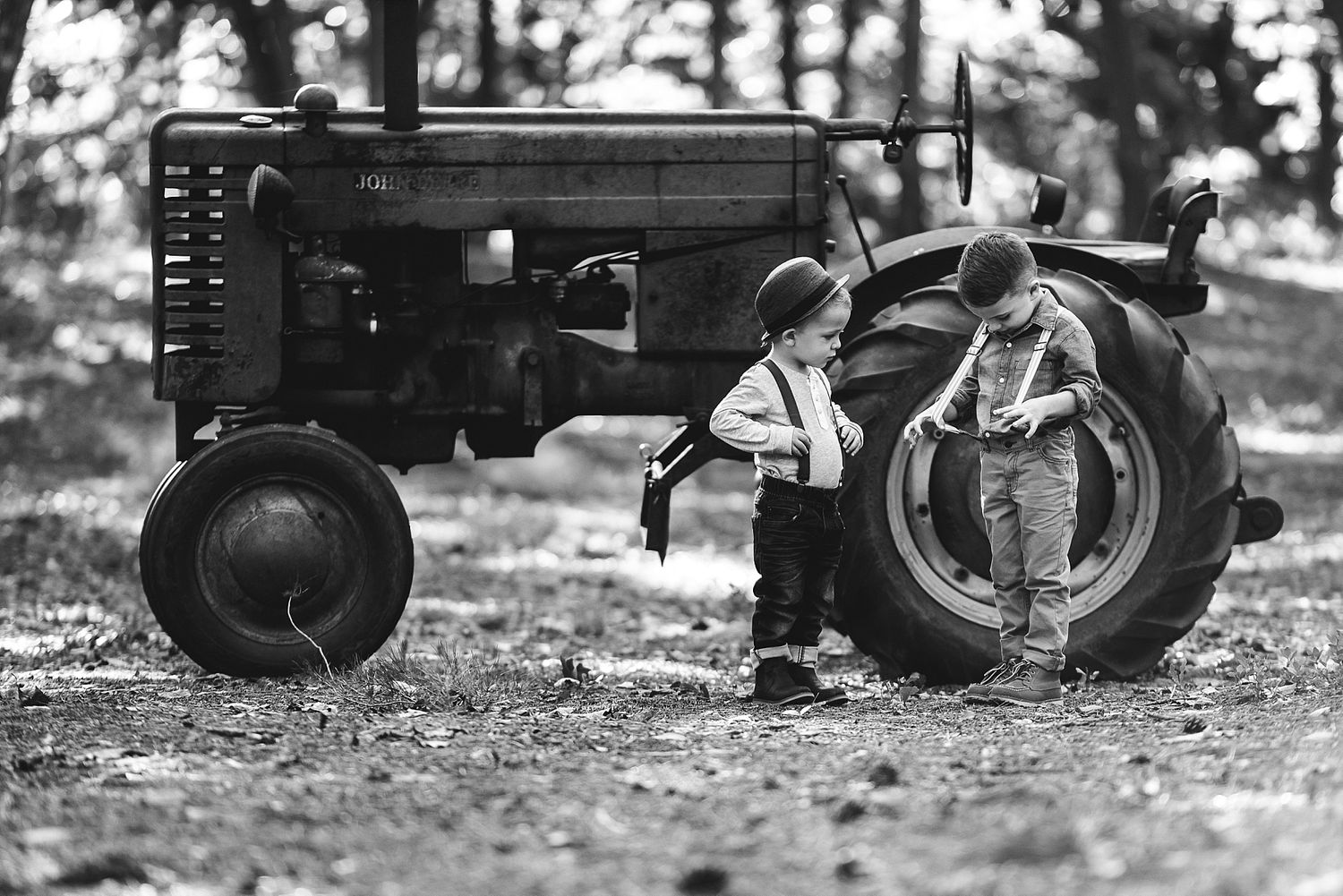 Vintage black and white photo of children playing around an old farm tractor.
