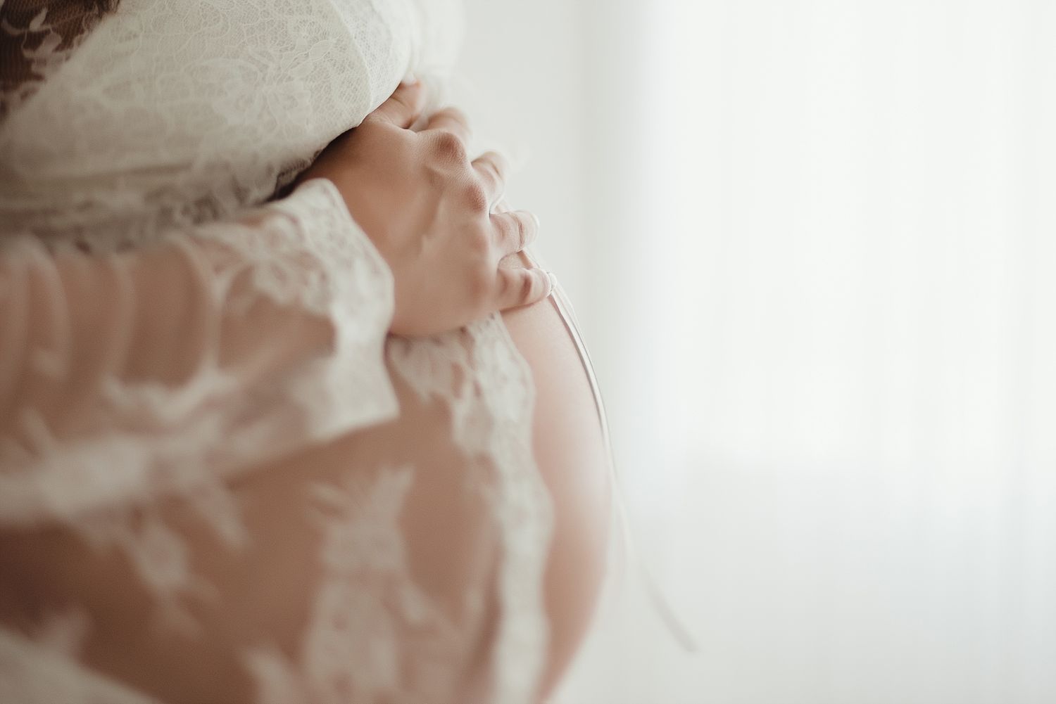 Close-up detail of delicate white lace fabric and hands in soft natural light.