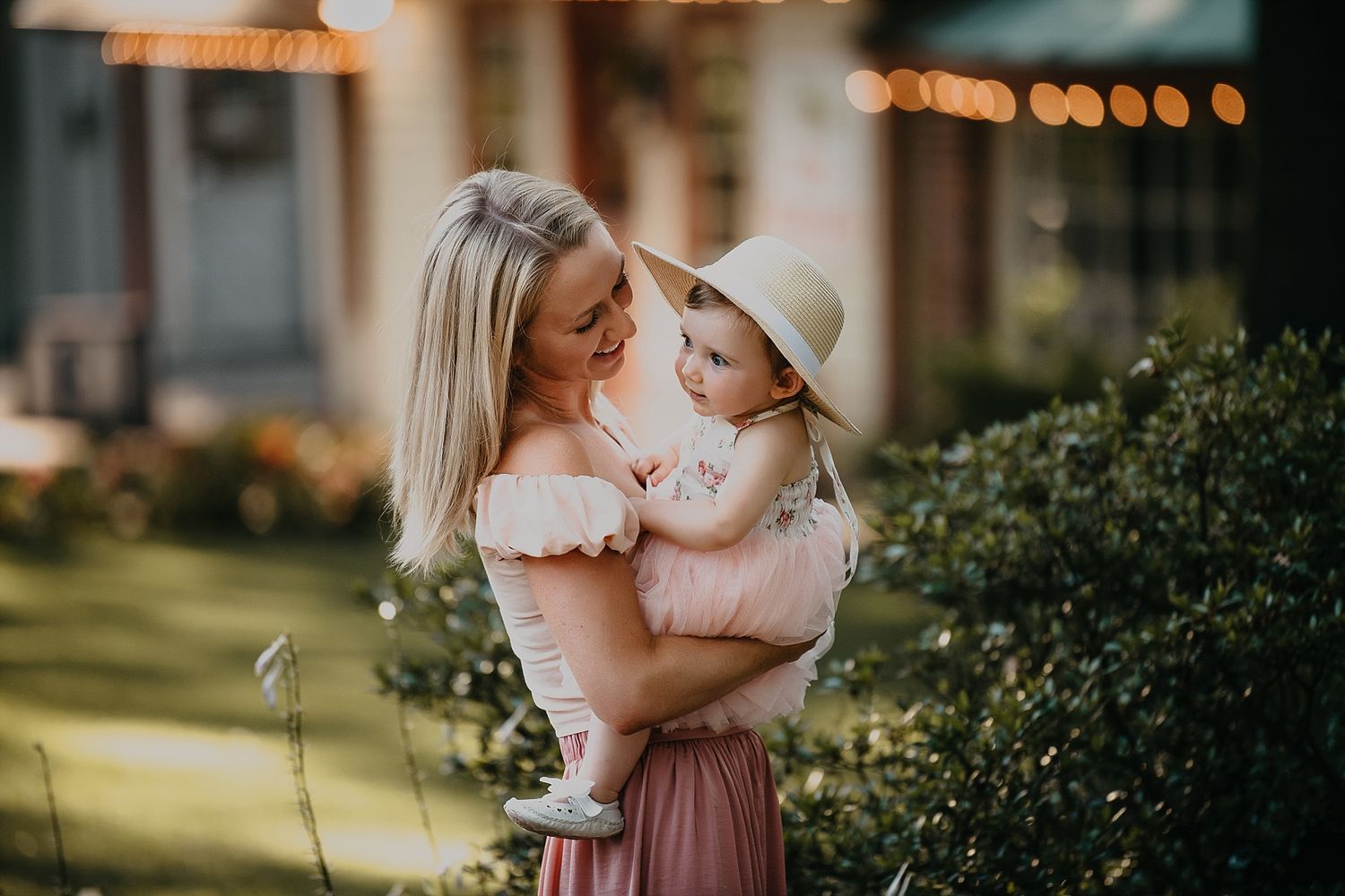 Mother and baby in sunlit garden with warm evening glow.