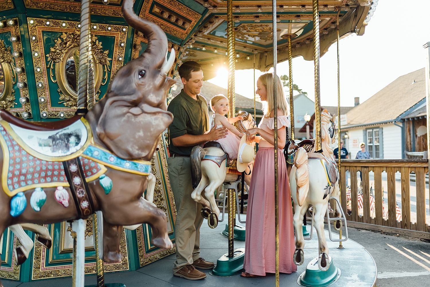 Family enjoying time together on vintage carousel with ornate painted horses.