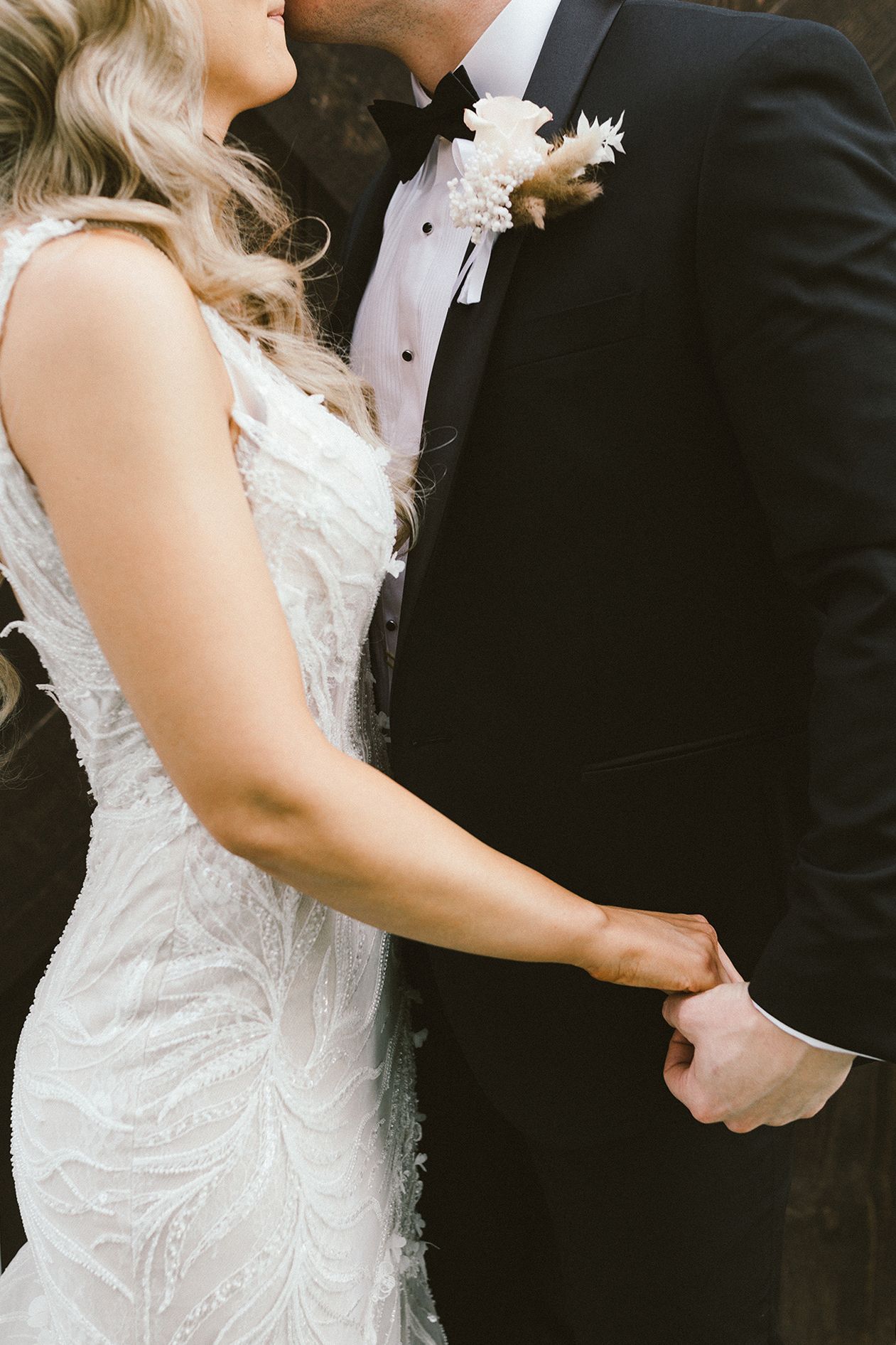 Close-up details of formal wedding attire showing black tuxedo and white lace dress.