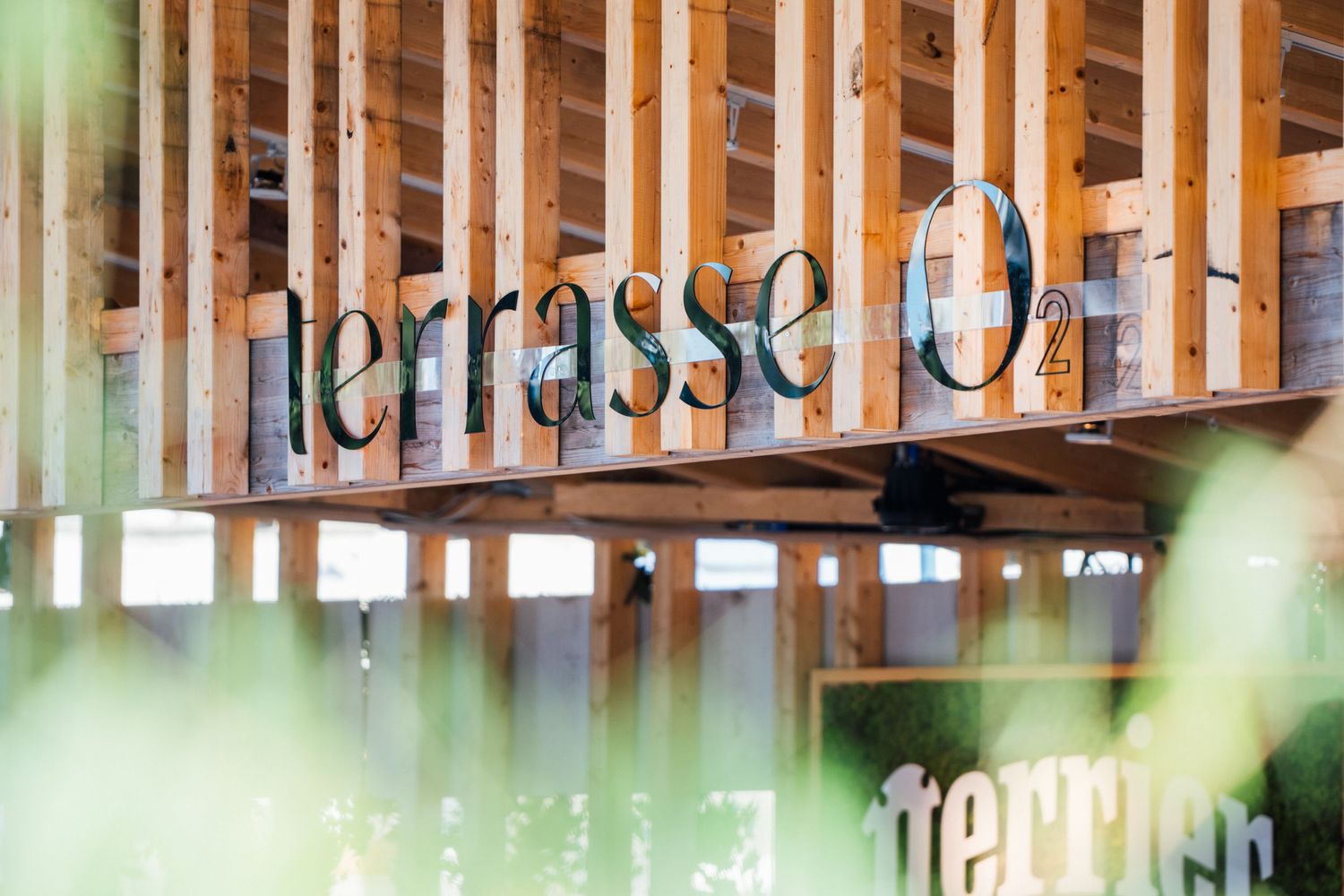 Illuminated restaurant signage with modern typography mounted on wooden beams.