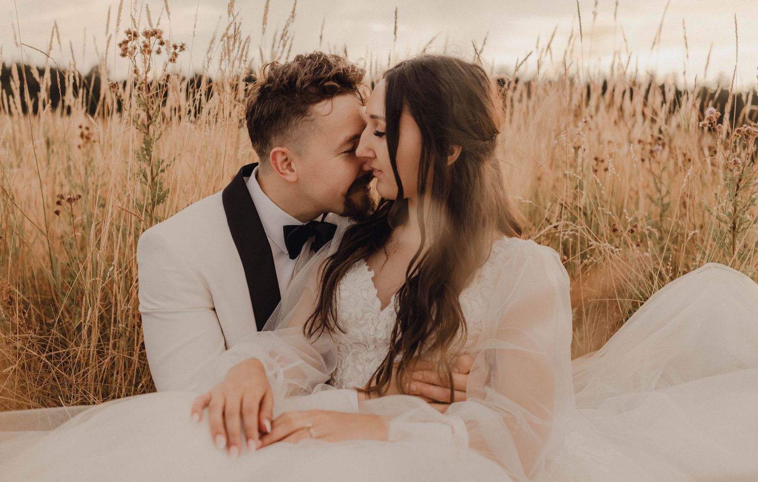 Newlywed couple sharing a serene moment in a windswept field