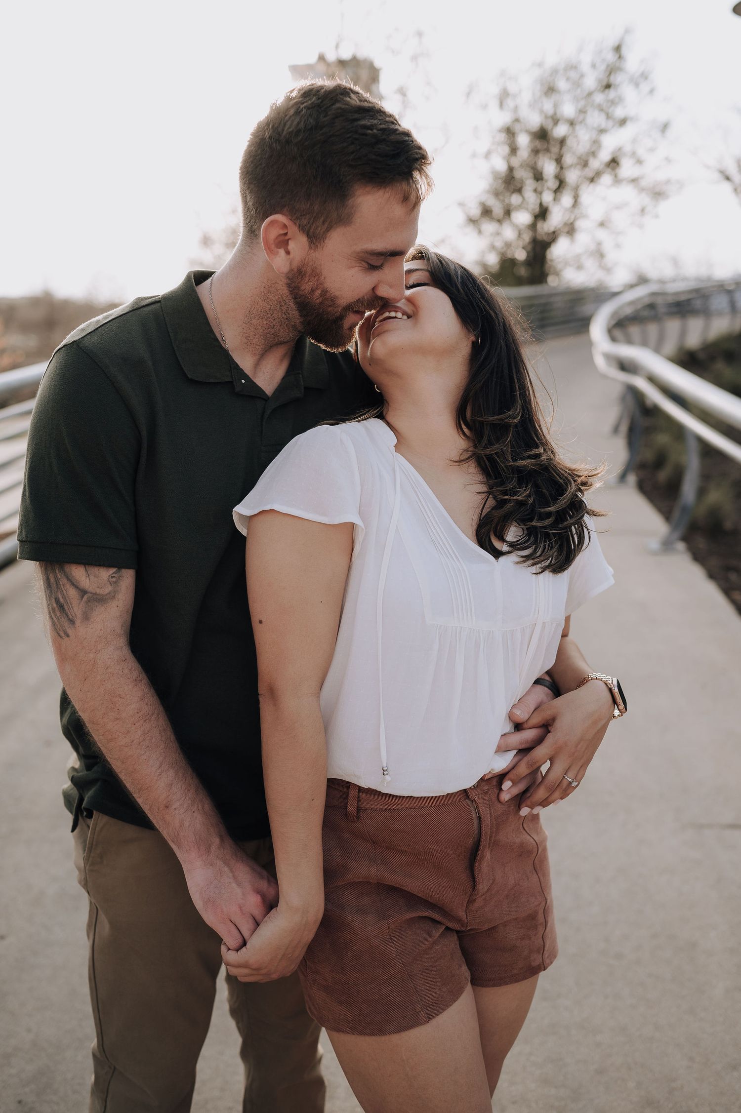 A couple in casual attire shares an intimate moment on an outdoor walkway.