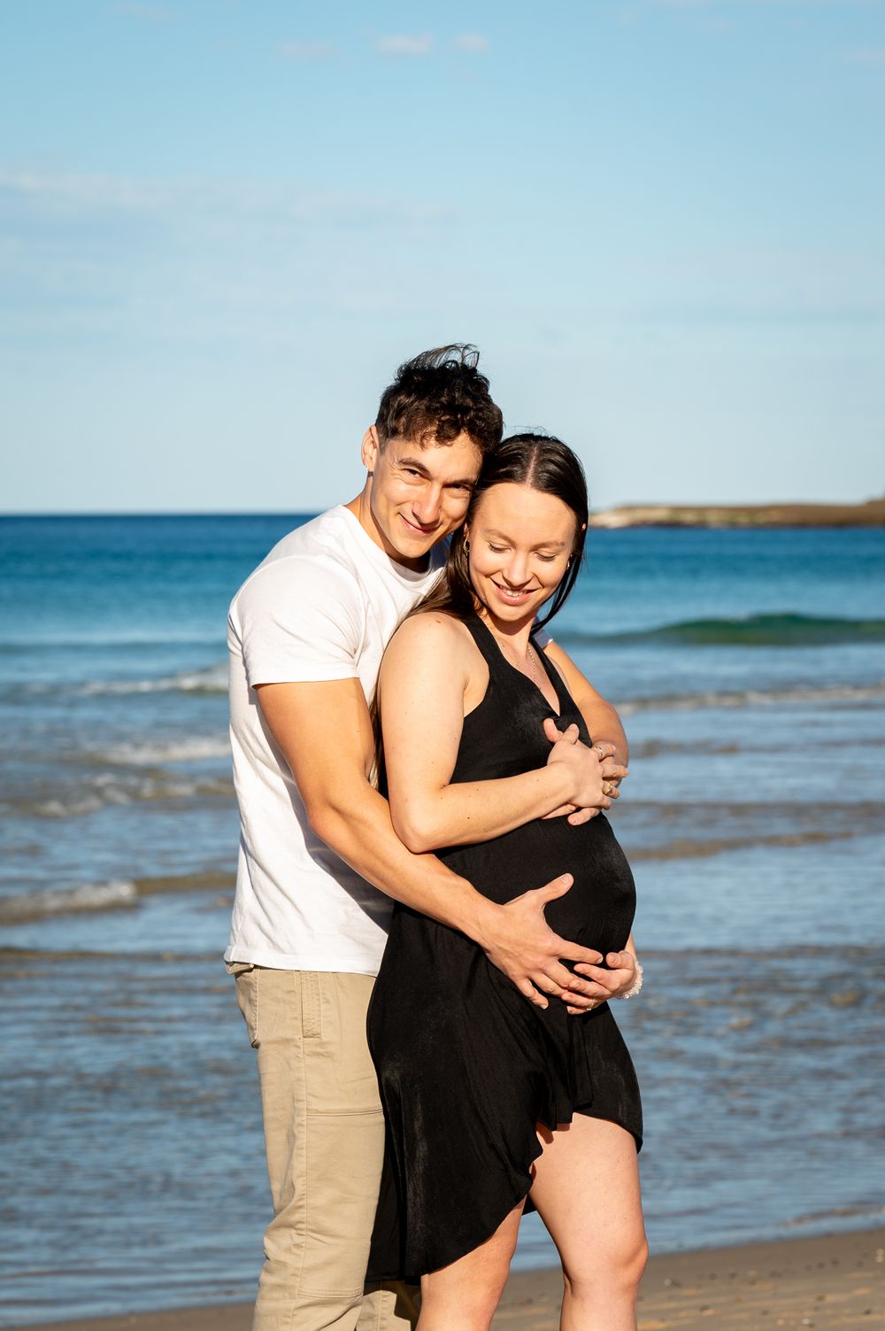 Fit young couple enjoying a cuddle while celebrating their baby bump