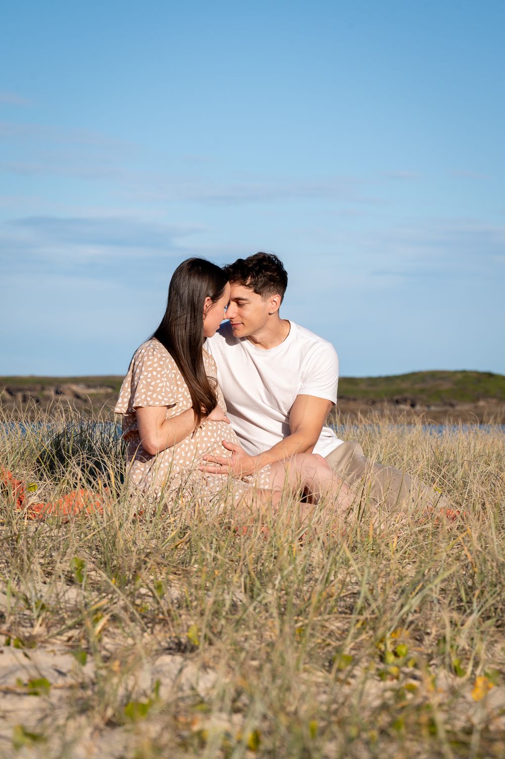 Mum to be enjoying a cuddle with her husband in the grass