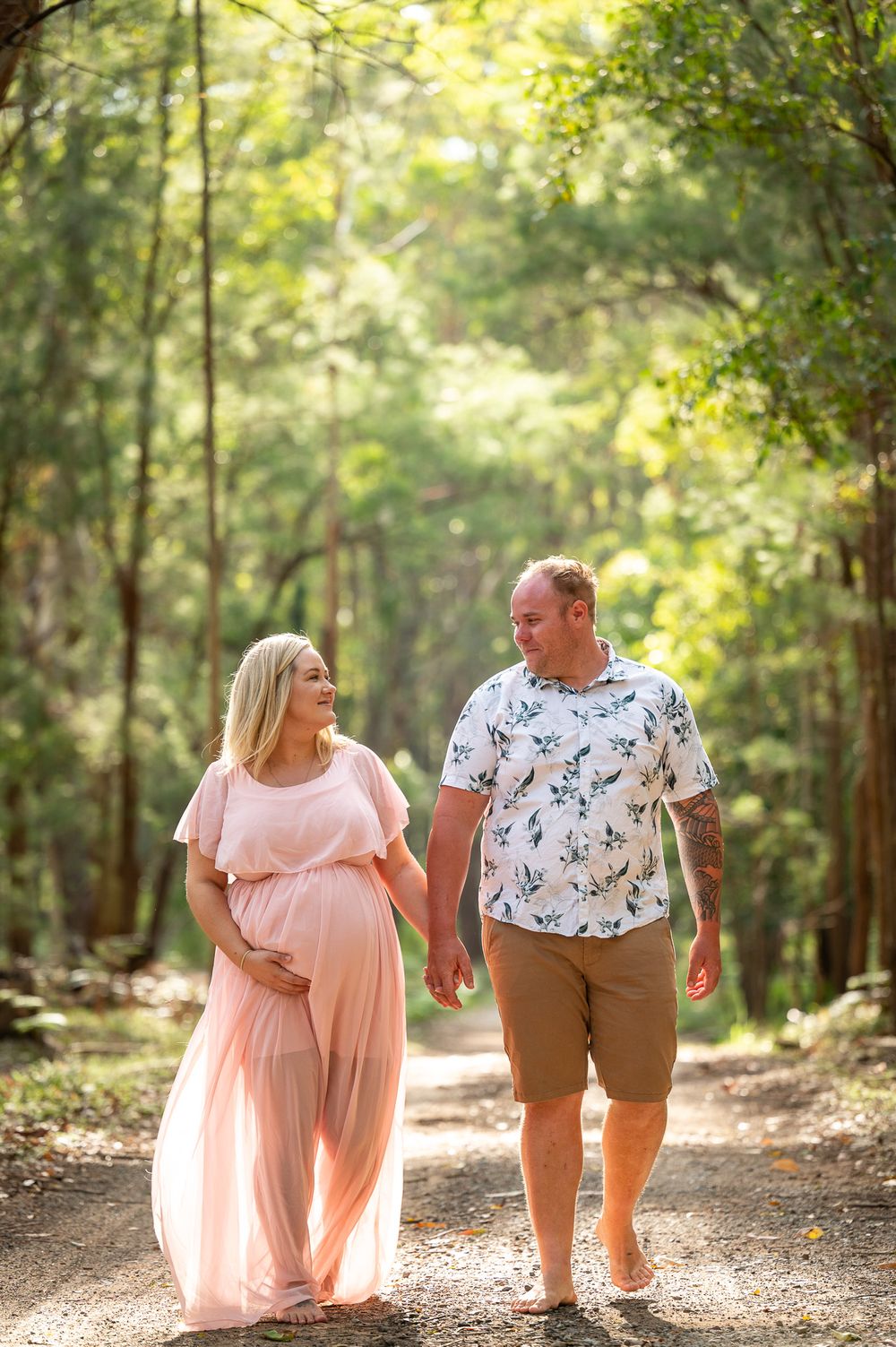 Mum to be walking in the bush holding hands during her photoshoot