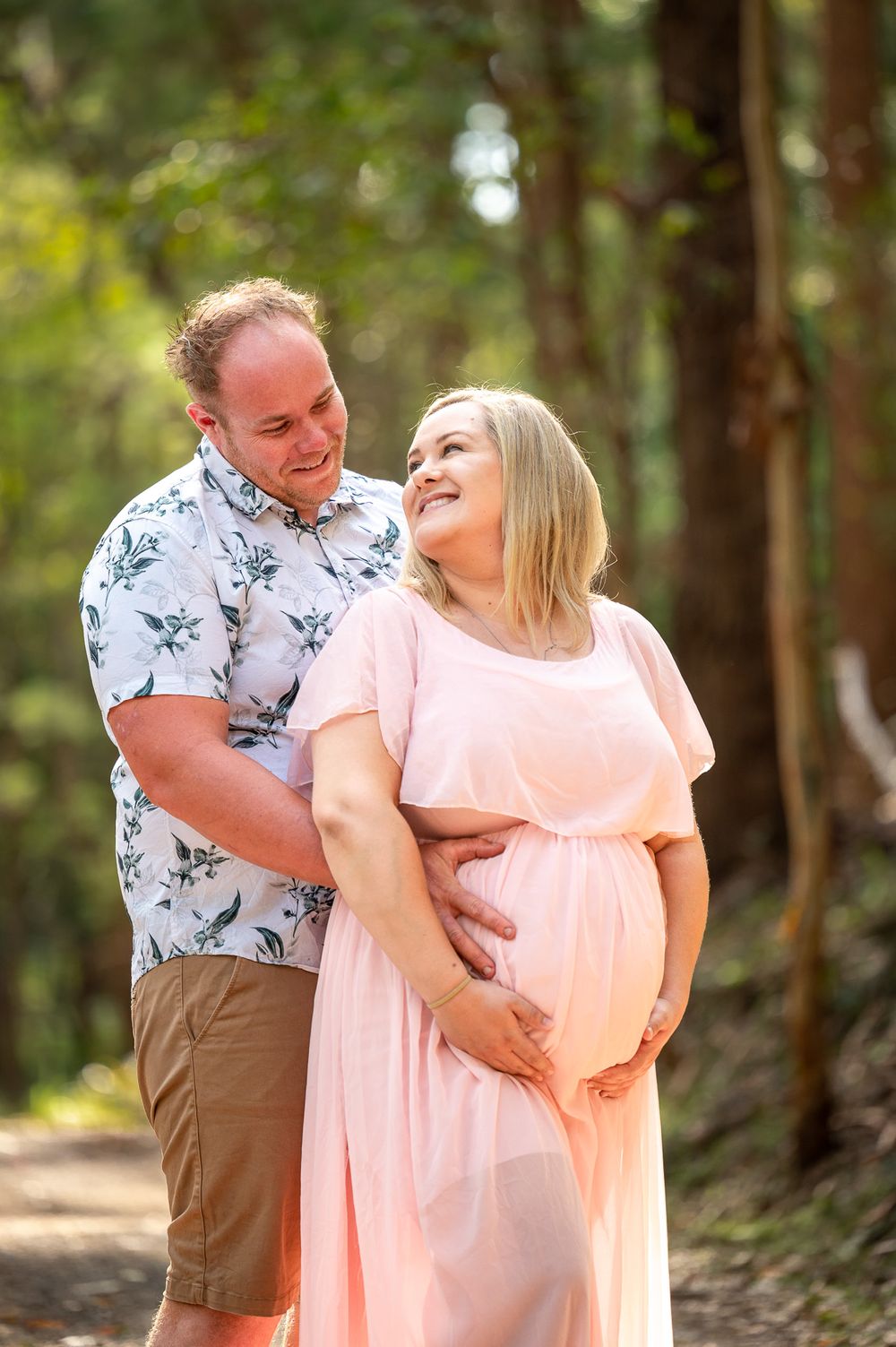 Mum to be being embraced by dad smilling at each other