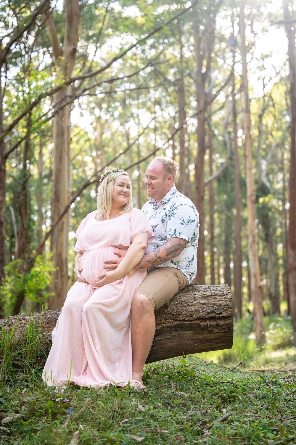 Mum to be sitting on a log with her partner having a hug
