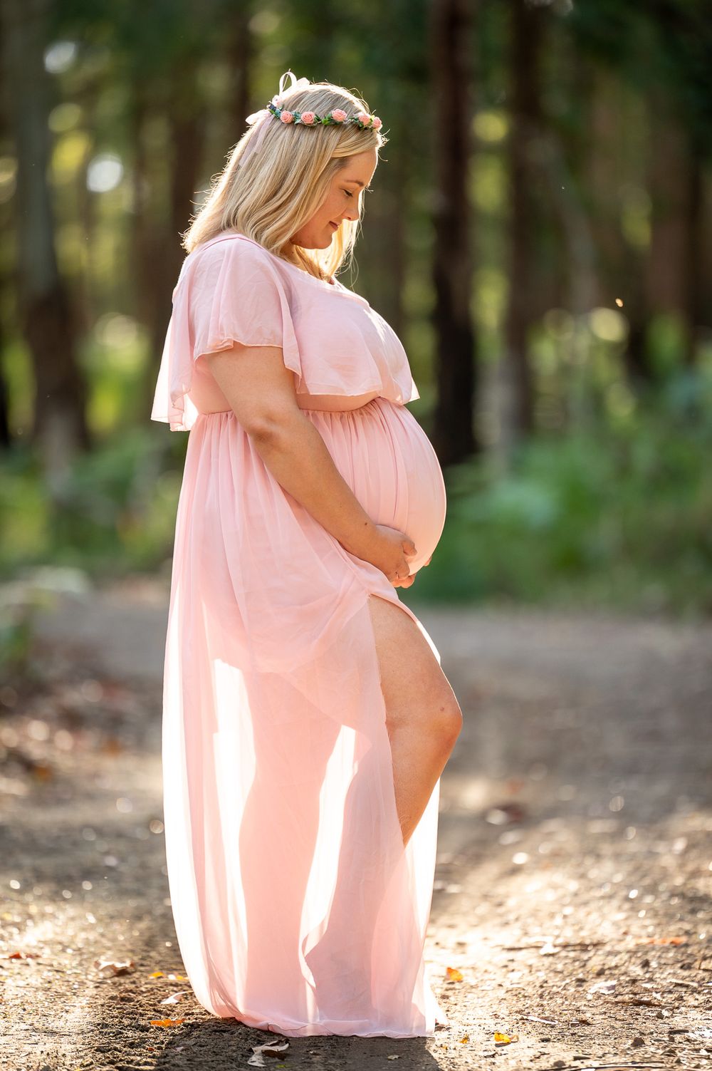 Mum to be lovingly looking at her baby bump in the bush