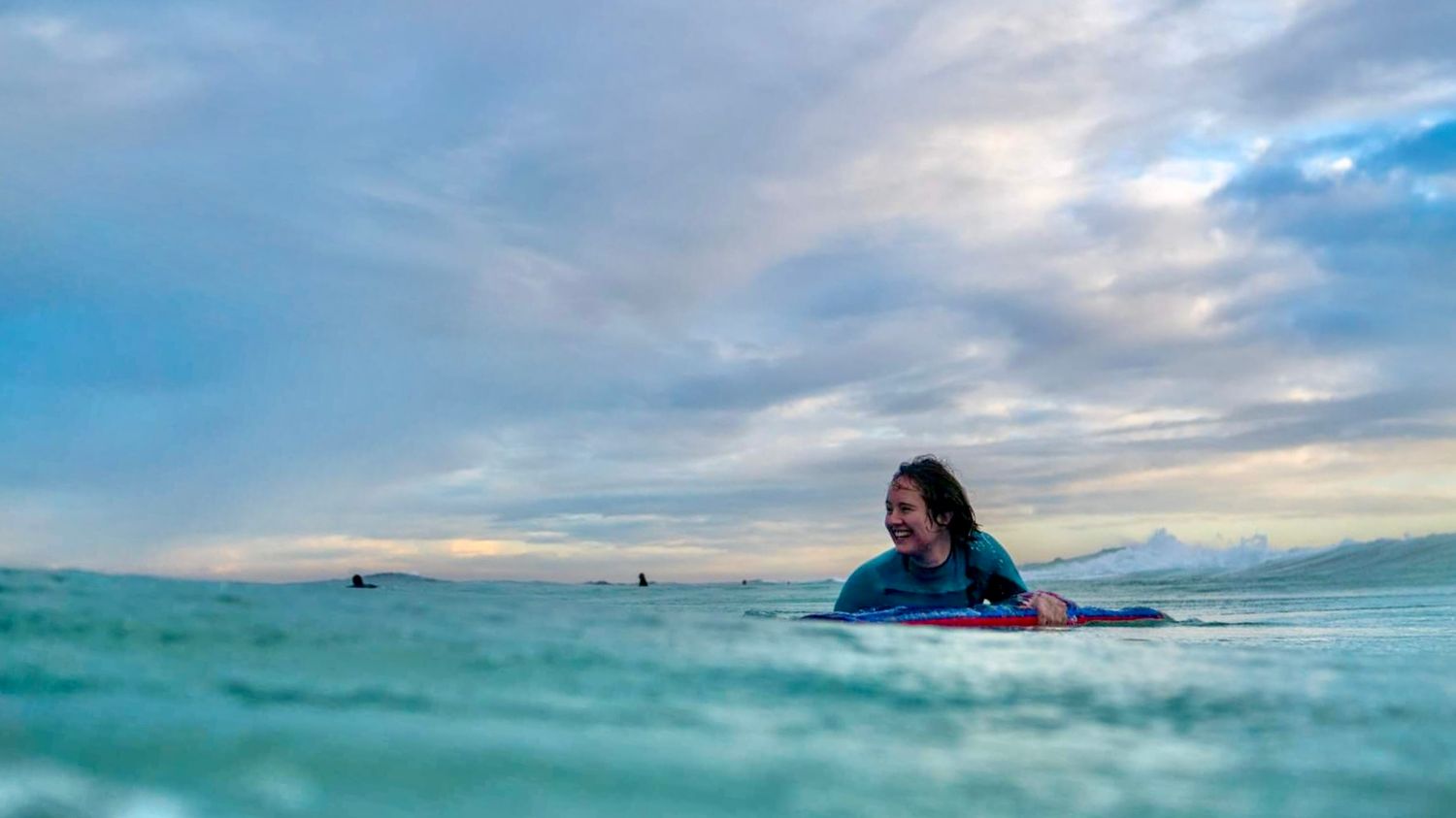 Cassie in the water at sunrise on a body board.