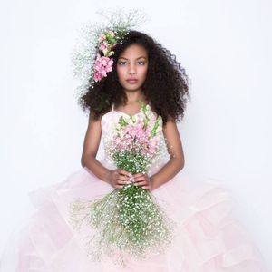 A dreamy portrait with delicate pink flowers and baby's breath bouquet against a soft tulle dress in a romantic setting.