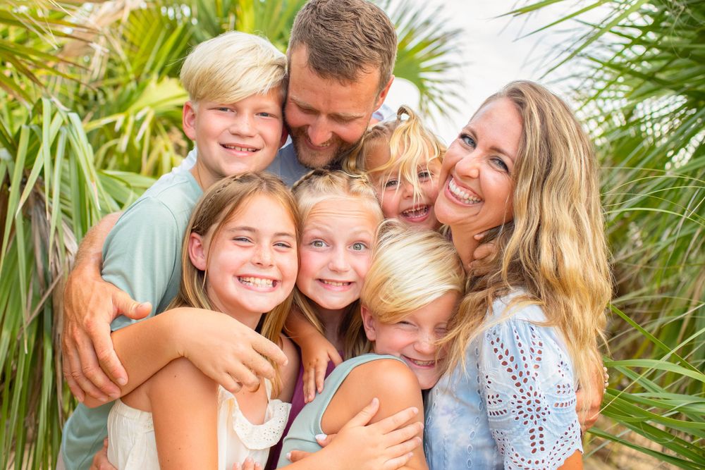 family with 5 kids at  the beach with palms smiling at the camera
