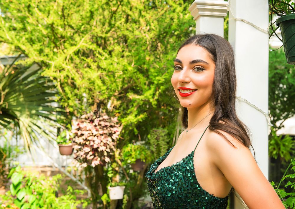 Sparkling emerald evening dress showcased against lush garden and architectural elements.