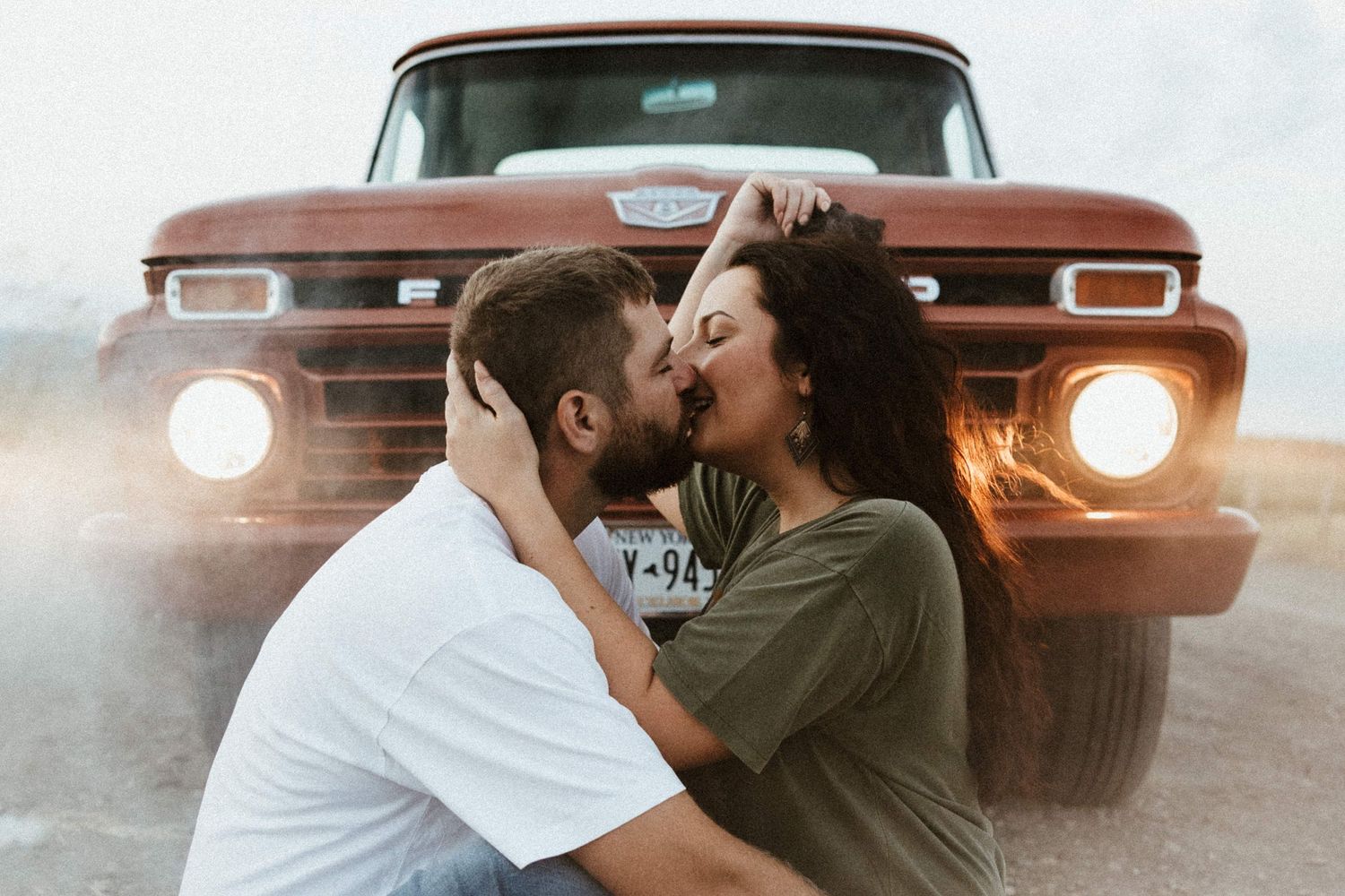 a couple kissing in front of a classic pickup truck on a dirt road in the finger lakes