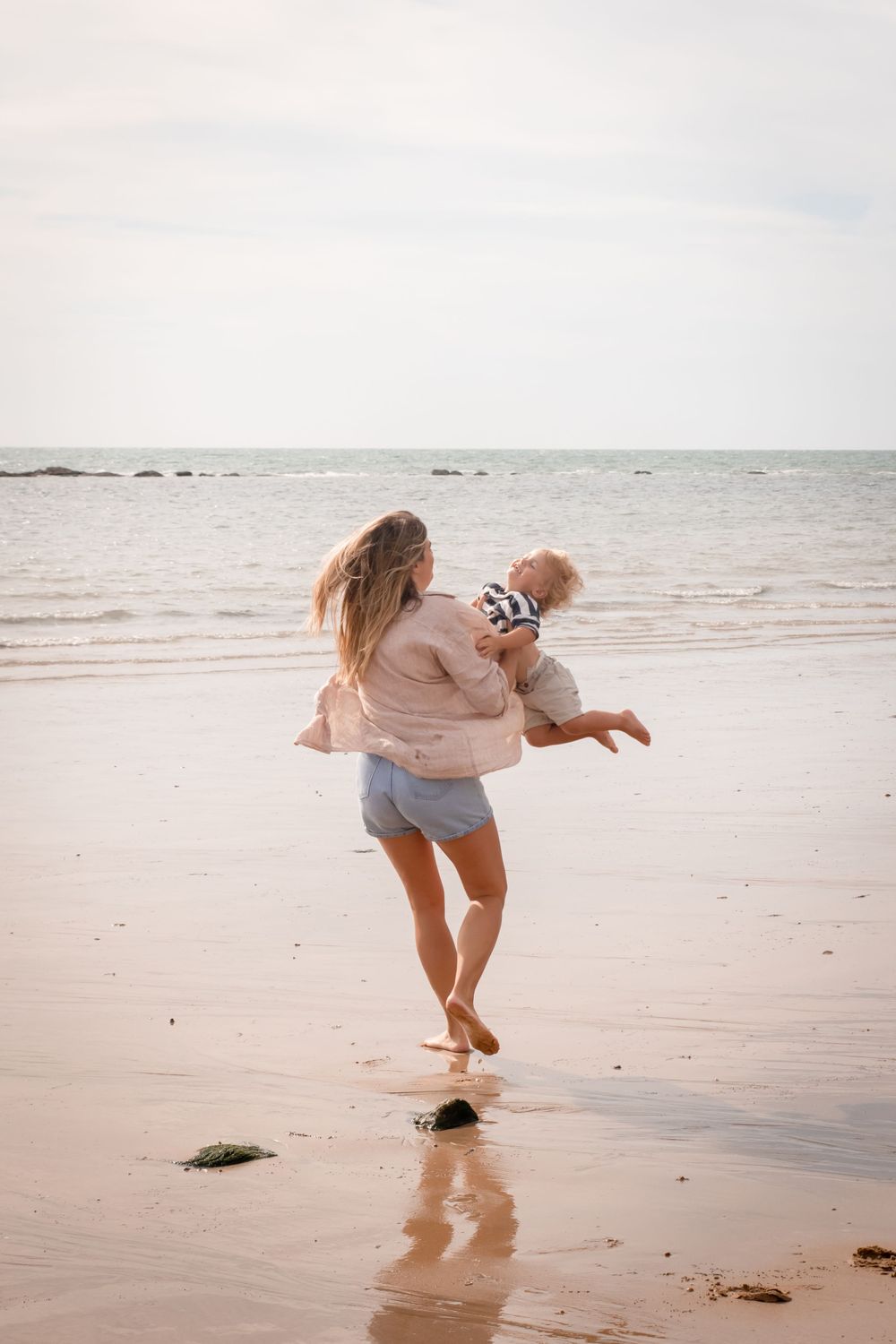 A mother plays with her baby son on Eastbourne beach for a family photoshoot