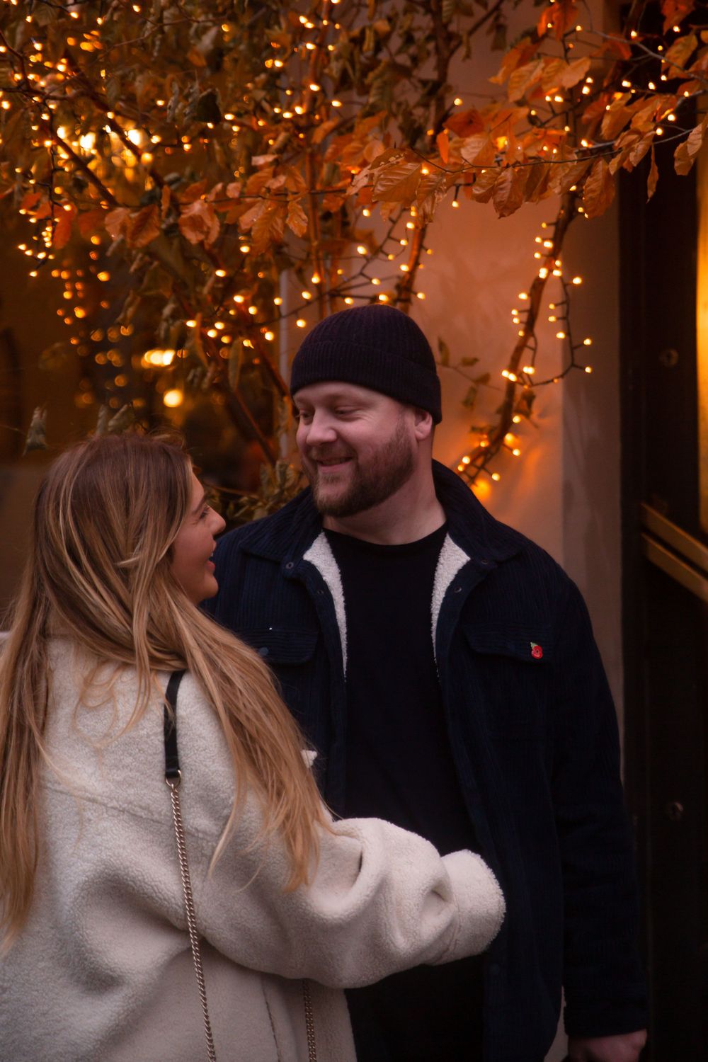 A couple smiling at each other in the Christmas lights at Arundel Castle photoshoot