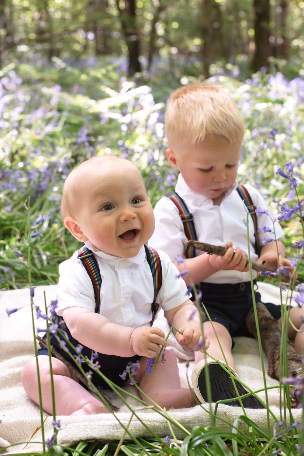 Two brothers sitting and playing in the bluebells in eastbourne for a family photoshoot
